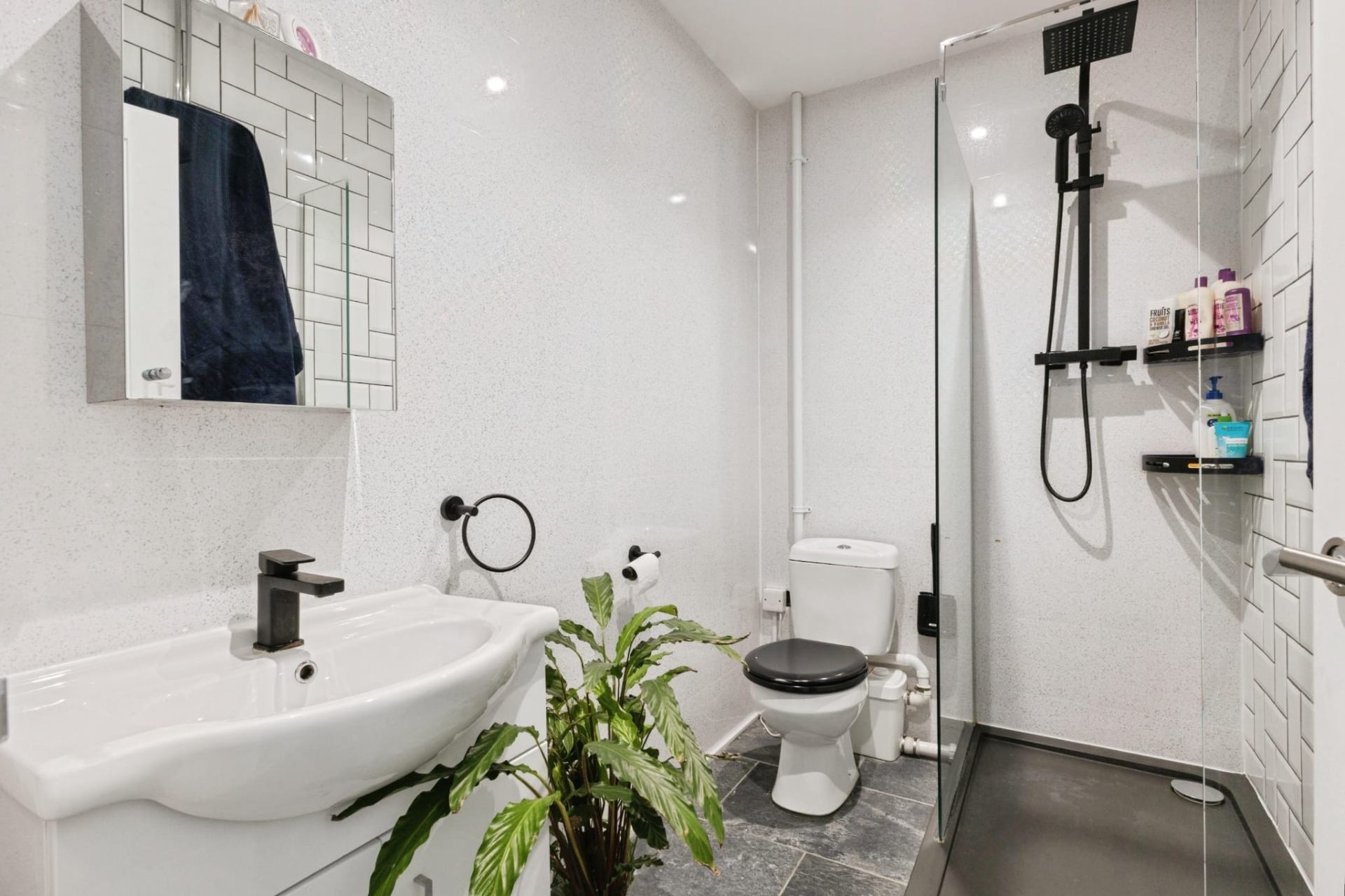 Bright white bathroom with walk-in shower, black fixtures and a modern white vanity